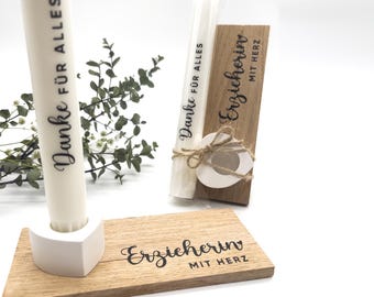 May include: A white candle with the text "Danke für Alles" and a wooden base with the text "Erzieherin mit Herz". The candle is displayed with a white heart-shaped candle holder and a small bundle of eucalyptus.