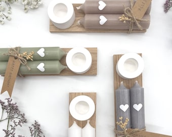 May include: Assortment of decorative candles in various colors, including gray, white, and green, each adorned with heart-shaped accents. Some candles are paired with wooden holders and tags that read "Alles Liebe", "Happy Birthday", and "Dankeschön".