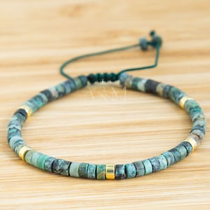 May include: A green and gold beaded bracelet with a sliding knot closure. The bracelet is made with small, round beads and features a gold accent bead.