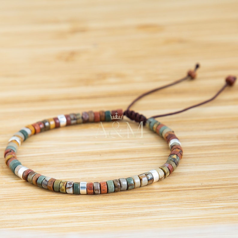 May include: A brown leather cord bracelet with multi-colored stone beads and silver beads. The bracelet is adjustable with a sliding knot.