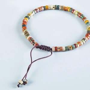 May include: A multi-colored beaded bracelet with a brown cord closure. The beads are made of various stones and have a natural, earthy look.