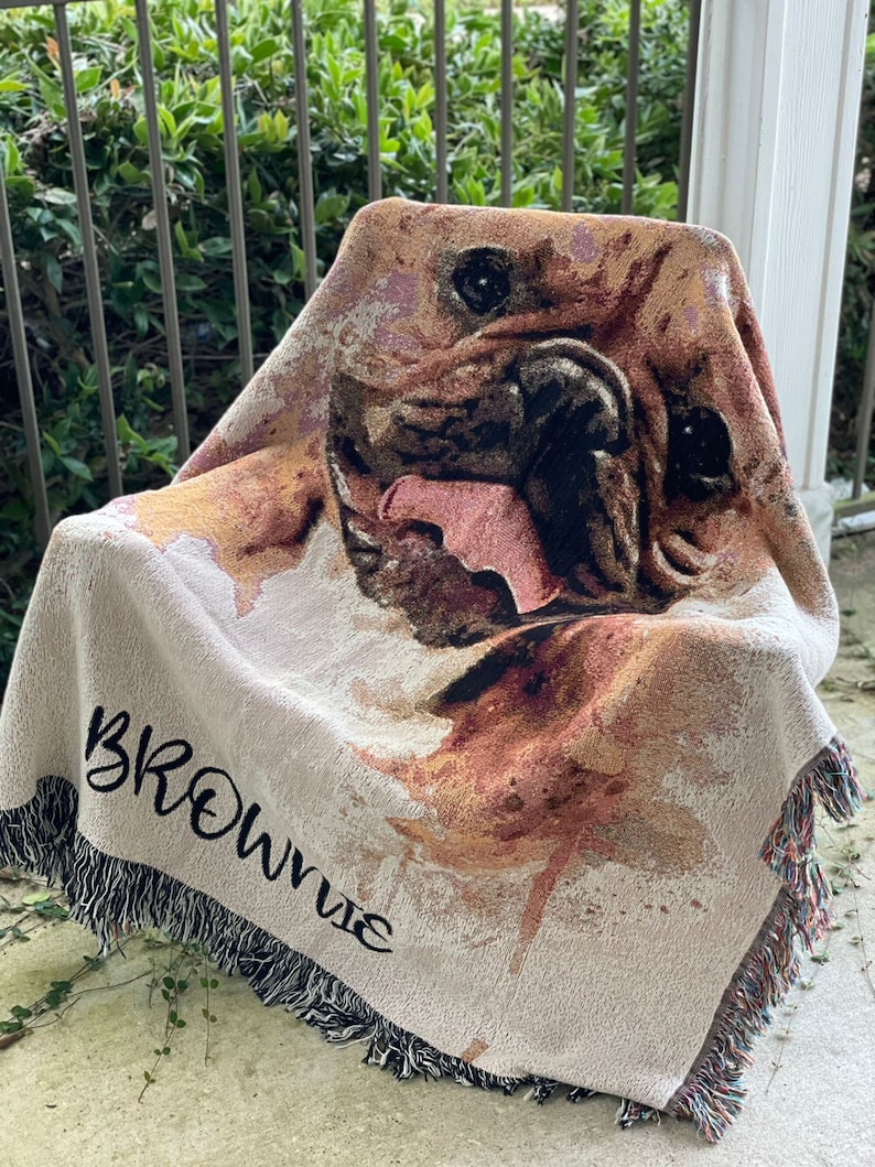 May include: A woven throw blanket with a watercolor-style image of a dog's face. The blanket has a fringe border and the name "Brownie" is woven into the bottom corner.