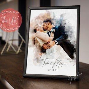 May include: A watercolour painting of a couple kissing on their wedding day. The painting is in a black frame and has the couple's names and wedding date, "Taylor & Morgan 09.18.21", written below the image.
