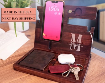 May include: A wooden phone stand with a leather wallet holder, a small white wireless charger, and a key hook. The stand has a personalized inscription that reads "M Miller".