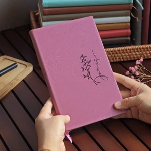 May include: A pink leather-bound journal with a floral design and the word "always" written in cursive on the front cover.