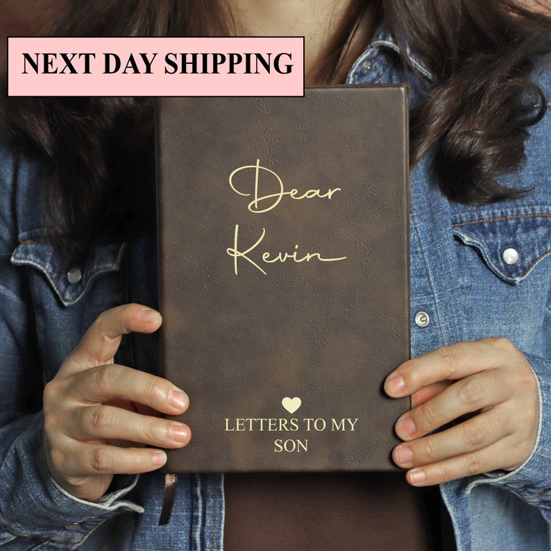 May include: A brown leather journal with gold lettering that says "Dear Kevin" and "Letters to My Son". A heart symbol is above the text "Letters to My Son".