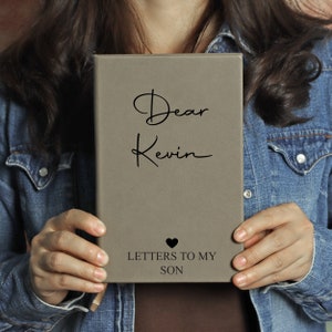 May include: A grey leather-bound journal with the text "Dear Kevin Letters to My Son" and a small heart symbol.