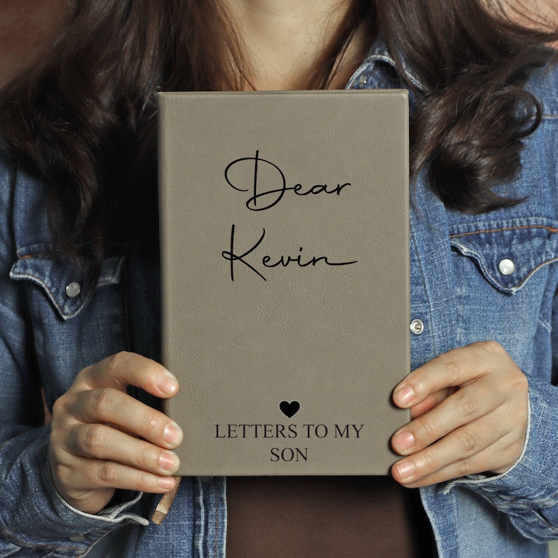 May include: A grey leather-bound journal with the text "Dear Kevin Letters to My Son" and a small heart symbol.
