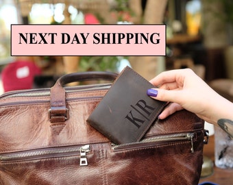 May include: A brown leather wallet with the initials "KIR" embossed on the front. The wallet is being placed into a brown leather bag. The text "NEXT DAY SHIPPING" is displayed in a pink banner above the image.