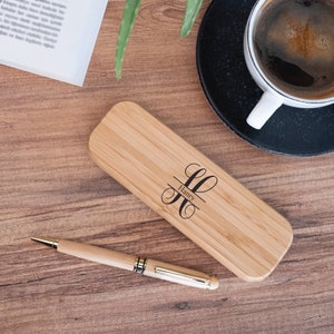 May include: A personalized bamboo pen case with a gold pen and the name "Harry" engraved on the case.