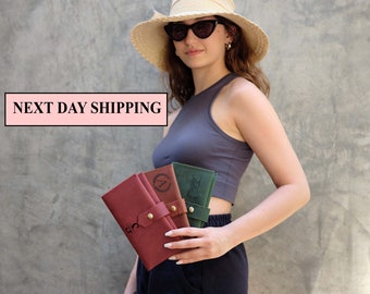 May include: Three leather wallets in different colors, brown, green, and black, with personalized initials and a decorative design. The wallets are held by a person wearing a gray tank top and a straw hat.