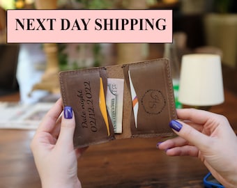 May include: Brown leather wallet with a card slot and a billfold. The wallet is engraved with the text "Date night 02/11/2022" and the initials "SH" in a wreath.
