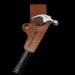 May include: A brown leather hammer holster with the word "HAMMERE" engraved on it. A silver hammer with a black rubber handle is in the holster.
