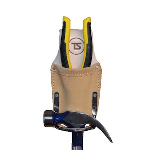 May include: A tan leather tool belt with a hammer and pliers. The belt has a white leather pocket with the letters "TS" in a circle.