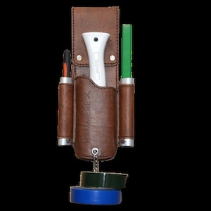Op de afbeelding: Een bruine leren gereedschapsriem met een wit utility mes, een groen gereedschap en twee oranje en zwarte gereedschappen. De riem heeft een metalen lus met twee rollen tape die eraan hangen.