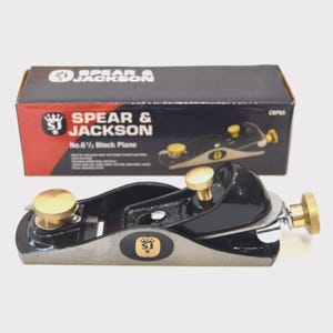 May include: A black and silver block plane with brass adjustment knobs and a wooden handle. The product is a Spear & Jackson No.6 1/2 block plane. The packaging displays the brand name and product details.