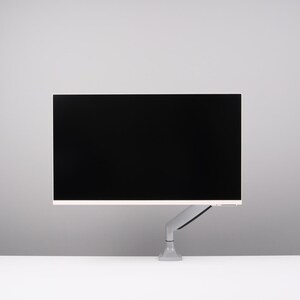 May include: A modern computer monitor with a black screen, mounted on a gray adjustable arm. The monitor has a thin white border and is set against a white and gray background. The arm is attached to a gray base.