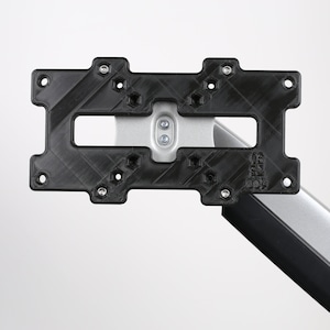 May include: A black plastic monitor mount with a silver arm and the text "ICY BOX" printed on the arm. The mount has multiple screw holes and a textured surface.