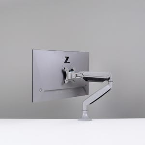May include: A silver computer monitor with a black "Z" logo on the back is mounted on a white and gray adjustable arm. The arm is attached to a white base, and the monitor is set against a gray background.
