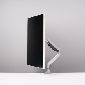 May include: A modern computer monitor with a black screen is mounted on a gray, adjustable arm. The arm is attached to a gray base, and the setup is on a white surface against a gray background. The monitor is oriented vertically.
