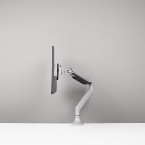 May include: A grey computer monitor mounted on a white and grey adjustable arm. The arm is attached to a white base, allowing for flexible positioning. The monitor is angled to the side.
