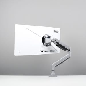 May include: A white Acer computer monitor attached to a silver and black adjustable arm. The monitor is set against a light grey backdrop, displaying the rear of the screen and the mounting hardware.