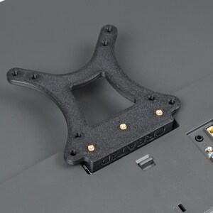 May include: A black, textured, 3D-printed bracket with brass-coloured screws, designed to mount on a grey surface. The bracket has a unique shape with multiple mounting holes and the text "CREATE3D" is visible.