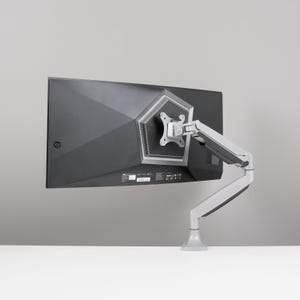 Puede incluir: Un monitor de ordenador negro con un soporte de brazo articulado plateado y gris. El monitor está montado sobre una superficie blanca sobre un fondo gris. El soporte del brazo permite un posicionamiento flexible.