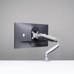 May include: A black computer monitor with a silver adjustable arm mount. The monitor has a logo on the back. The arm mount is attached to a white surface against a gray background. The monitor is designed to be mounted on a desk.