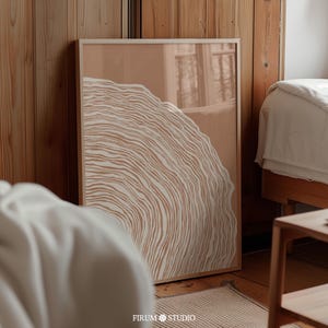 May include: A framed abstract print with a brown background and a white, wavy, circular design. The print is in a wooden frame and is hanging on a wall.