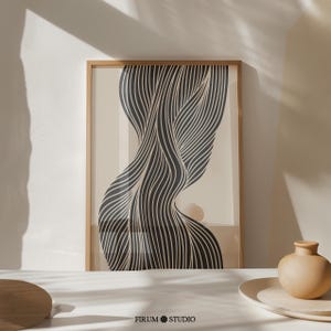 May include: A black and white abstract line art print in a wooden frame. The lines are curved and flowing, creating a sense of movement. The print is on a beige background.