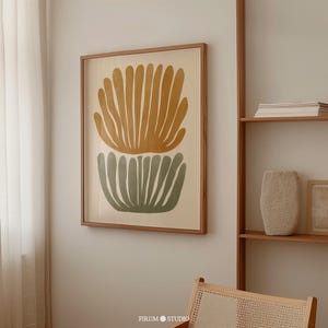 Può includere: Una stampa artistica da parete incorniciata che raffigura due forme botaniche astratte a ventaglio sovrapposte. La forma superiore è giallo senape, quella inferiore verde salvia. Entrambe sono su uno sfondo color crema in una cornice in legno chiaro.