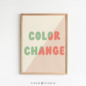 May include: A framed wall art print featuring the text COLOR CHANGE in rounded, bubble-style letters. The background is split diagonally between a cream color on the left and a soft peach color on the right, with the letters changing color accordingly.