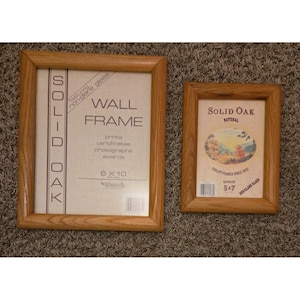 May include: Two rectangular solid oak wall frames with non-glare glass. The larger frame is labeled 8 x 10 and the smaller frame is labeled 5 x 7. Both frames feature light brown wood grain textures and include printed paper inserts with product details.