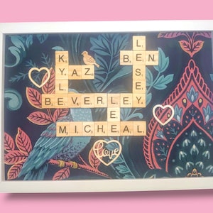 May include: A white frame with a dark blue background featuring a floral pattern. The frame contains a scrabble tile word art piece that spells out the names "Beverley" and "Michael" with the word "love" in a heart shape below.