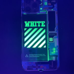May include: A white iPhone case with a green and white striped design and the word "WHITE" in green letters. The case is illuminated with a black light, making the design glow.