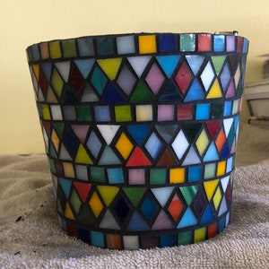 May include: A colorful mosaic planter with a geometric pattern of triangles and squares in shades of blue, green, red, yellow, and white.