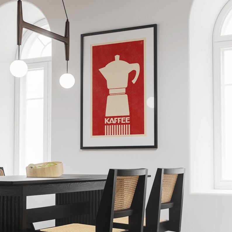 Pu&ograve; includere: Un poster incorniciato con sfondo rosso e una silhouette bianca di una caffettiera. Il testo "Kaffee" &egrave; stampato in bianco sotto la caffettiera.