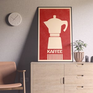 Pu&ograve; includere: Un poster rosso con una silhouette bianca di una caffettiera e la parola "Kaffee" in lettere bianche. Il poster ha un aspetto vintage con uno sfondo testurizzato.