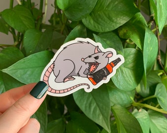 May include: A sticker of a gray rat holding a bottle of Jack Daniel's whiskey in its teeth.