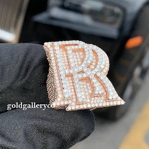 May include: A rose gold initial pendant with a large, sparkling diamond-encrusted letter "R".