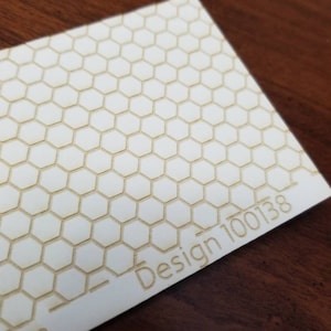 May include: White rectangular piece of wood with a honeycomb pattern and the text "Design 100138" and "com" printed on the bottom right corner.