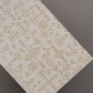 以下が含まれることがあります： 様々な幾何学的な形、円、矢印、十字架を含むベージュのパターンが施された白い表面。左下の隅に「Design 100484」というテキストが表示されています。