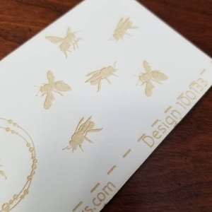 May include: White card with a design of bees in a repeating pattern. The text "papers.com - Design 10033" is printed on the card.