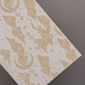 May include: White card stock with a repeating pattern of beige clouds and crescent moons. The text "Design 100482" is printed in the bottom left corner.