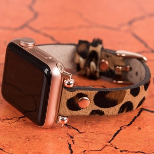 May include: A rose gold Apple Watch with a leopard print leather band. The band has a brown and black pattern.
