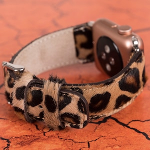 May include: A brown and black leopard print watch band with a rose gold Apple Watch face.