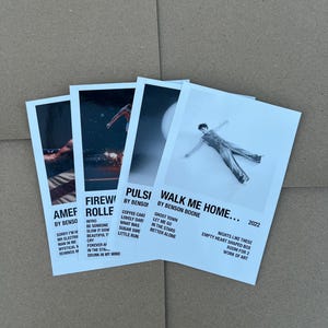 Könnte beinhalten: Vier weiße rechteckige Kunstdrucke mit schwarzem Text und Graustufenbildern. Die Drucke zeigen Songtitel und Künstlernamen. Der Druck rechts sagt "Walk Me Home..." von Benson Boone, 2022.