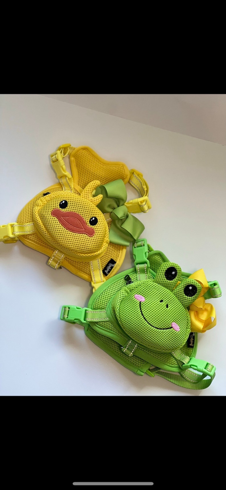 Puede incluir: Dos arneses para perros con un dise&ntilde;o de malla. Un arn&eacute;s es amarillo con un dise&ntilde;o de pato y un lazo verde. El otro arn&eacute;s es verde con un dise&ntilde;o de rana y un lazo amarillo.