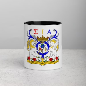 Może przedstawiać: Biały kubek ceramiczny z czarnym rantem i uchwytem. Kubek przedstawia kolorowy herb z koroną, jednorożcami i literami "ΣΙΑ". Tekst "SEMPER UNUM ET INSEPARABILIS" jest nadrukowany pod herbem.